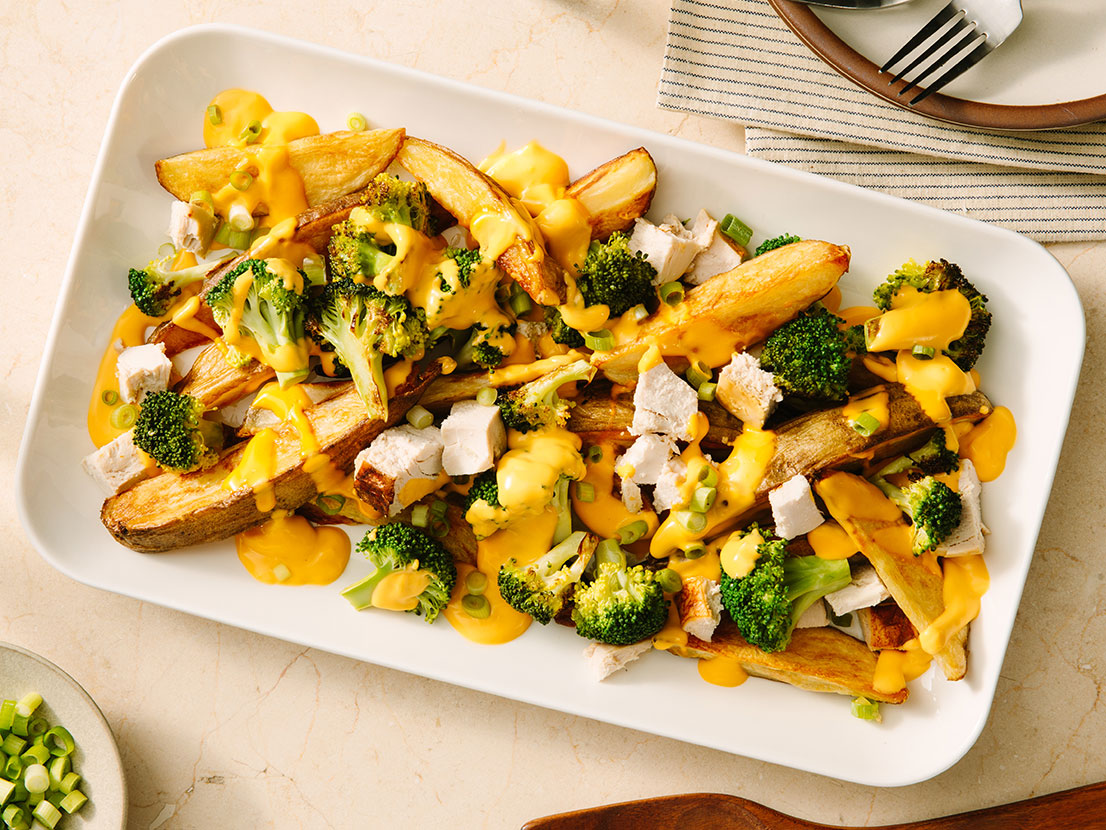 An image of prepared Cheesy Loaded Potato Wedges made with Prego® Creamy Cheddar Sauce, russet potatoes, broccoli, chicken and scallions.