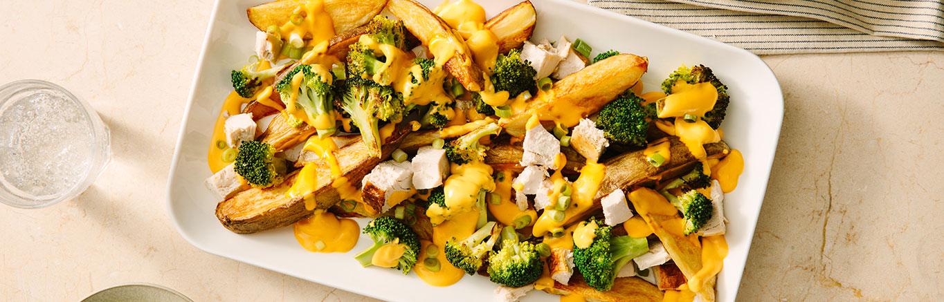 An image of prepared Cheesy Loaded Potato Wedges made with Prego® Creamy Cheddar Sauce, russet potatoes, broccoli, chicken and scallions.
