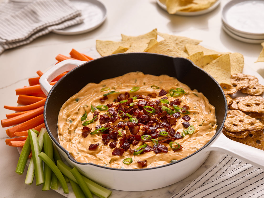 An image of prepared Cheesy Bacon Jalapeño Popper Dip made with Prego® Cheesy Bacon Cheddar Cheese Sauce, bacon, jalapeño, garlic, cream cheese and green onion.
