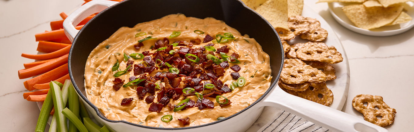 An image of prepared Cheesy Bacon Jalapeño Popper Dip made with Prego® Cheesy Bacon Cheddar Cheese Sauce, bacon, jalapeño, garlic, cream cheese and green onion.