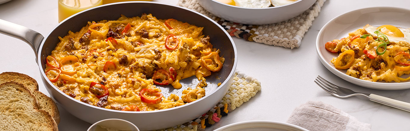 An image of prepared Cheesy Sausage, Pepper & Potato Breakfast Skillet made with Prego® Cheddar Cheese Sauce, bell peppers, hash brown potatoes, onions and pork sausage.