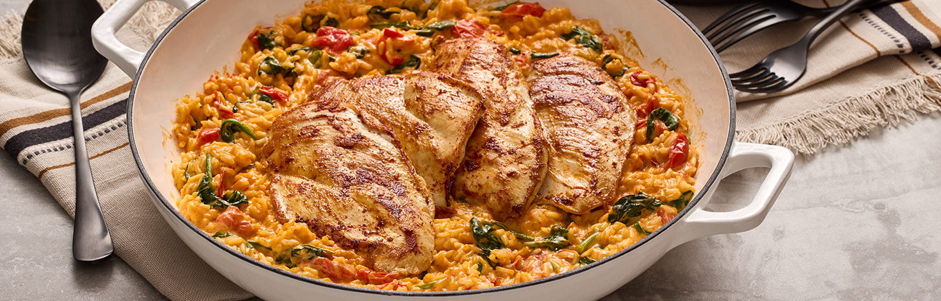 An image of prepared Creamy Cheddar Bacon Chicken & Rice made with Prego® Cheesy Bacon Sauce, chicken, milk, instant white rice, baby spinach and cherry tomatoes.