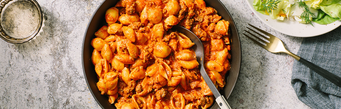 An image of prepared Creamy Tomato Beef & Shells made with Prego® Creamy Tomato with Ricotta Sauce, shell pasta, ground beef and Cheddar cheese.