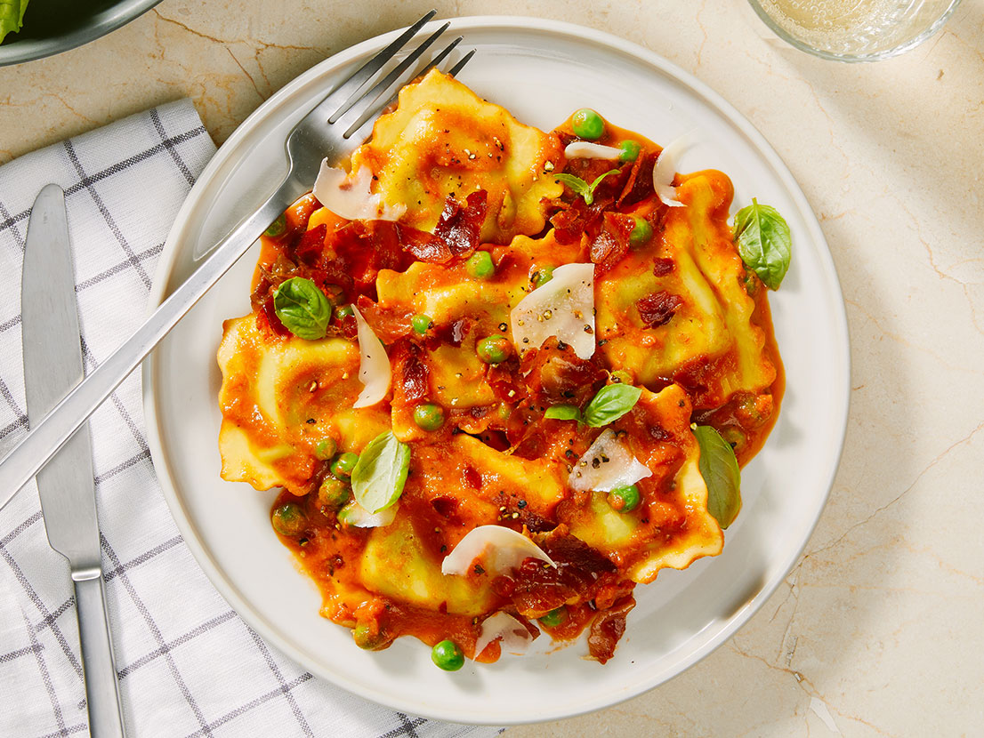 An image of prepared Creamy Tomato Ravioli with Proscuitto & Peas made with Prego® Creamy Tomato with Ricotta Sauce, proscuitto, ravioli, peas, Parmesan and basil.
