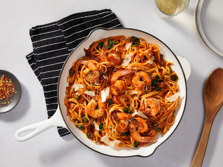An image of prepared Creamy Tuscan Shrimp Pasta made with Prego® Creamy Tomato with Garlic Sauce, baby spinach, linguine, onion, shrimp and sun-dried tomatoes.
