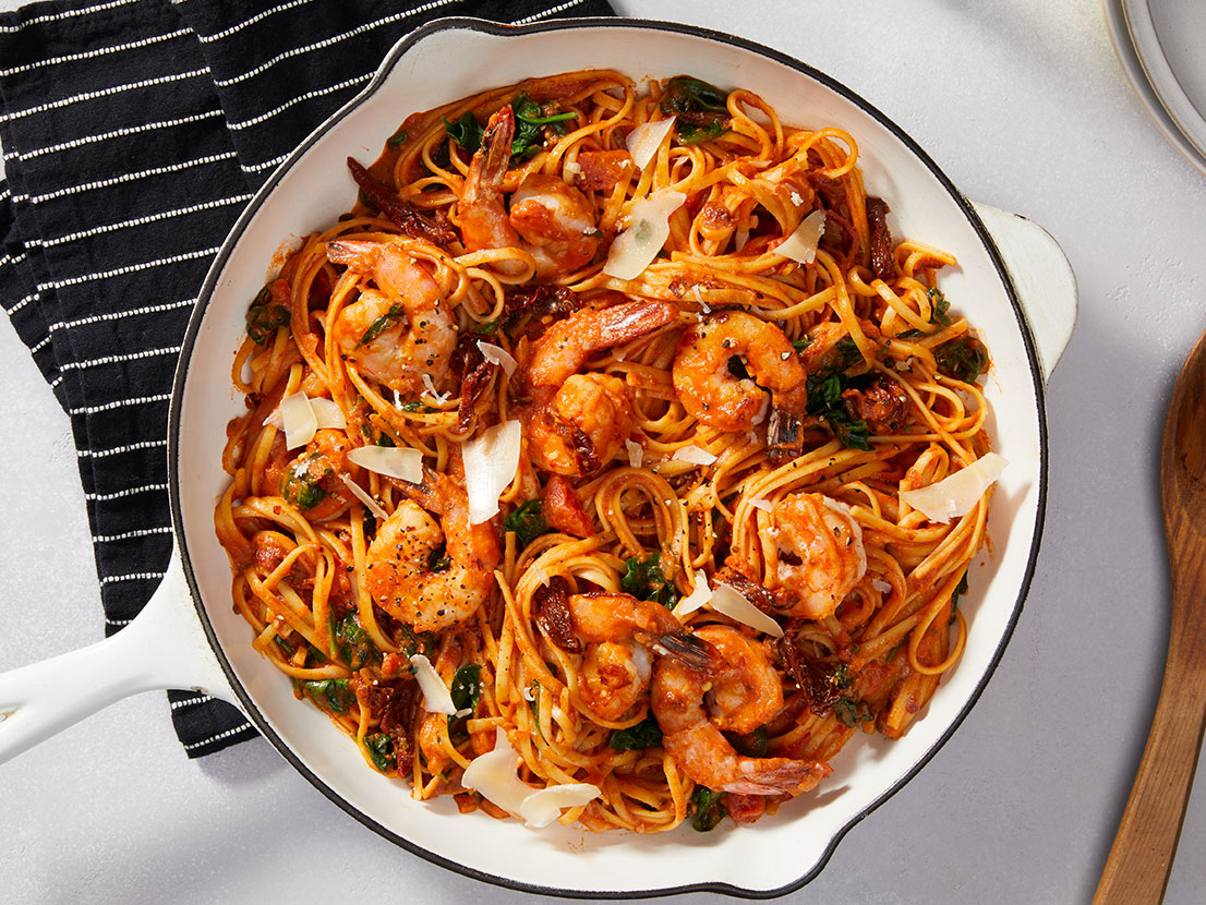 An image of prepared Creamy Tuscan Shrimp Pasta made with Prego® Creamy Tomato with Garlic Sauce, baby spinach, linguine, onion, shrimp and sun-dried tomatoes.