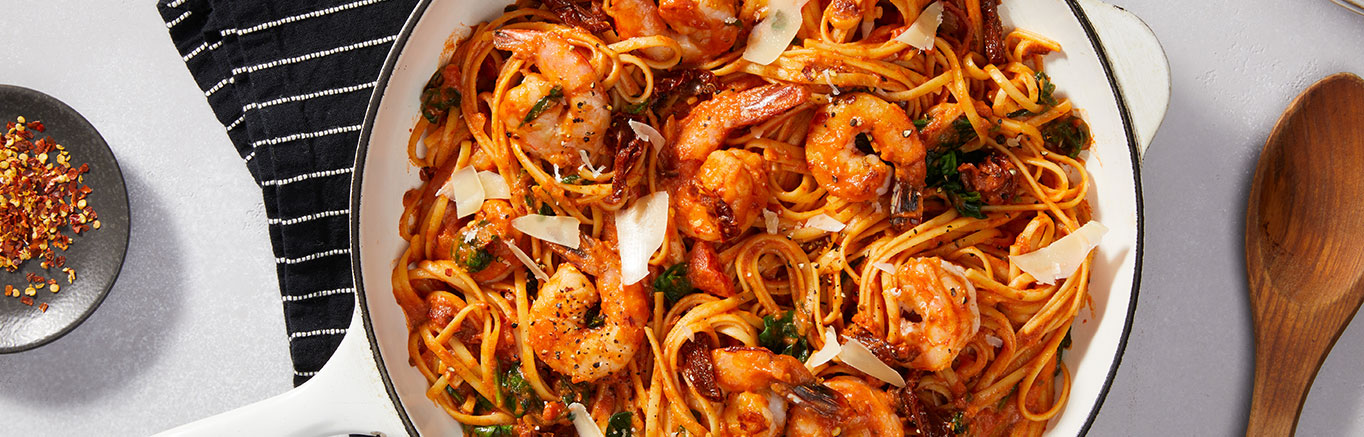 An image of prepared Creamy Tuscan Shrimp Pasta made with Prego® Creamy Tomato with Garlic Sauce, baby spinach, linguine, onion, shrimp and sun-dried tomatoes.