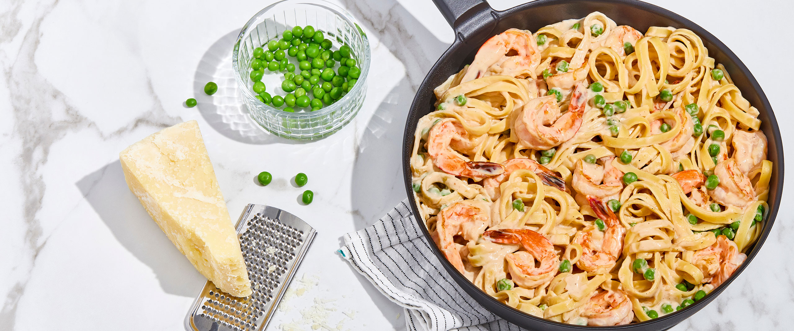An image of prepared Shrimp Alfredo made with fettuccine pasta, shrimp, Prego® Homestyle Alfredo Sauce, peas and basil.