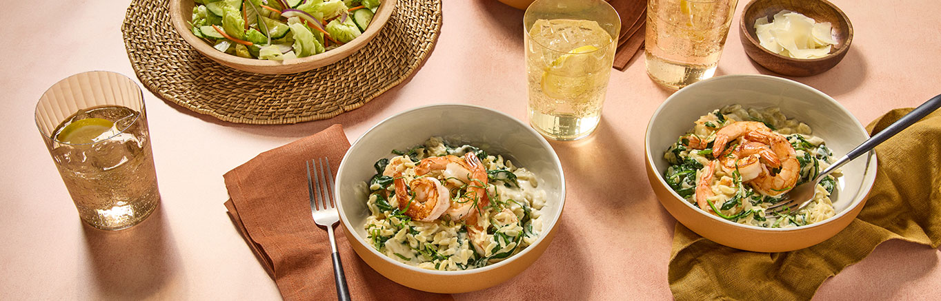 An image of prepared Creamy Lemon Orzo with Shrimp made with Prego® Lemon Alfredo Sauce, shrimp, spinach and orzo.