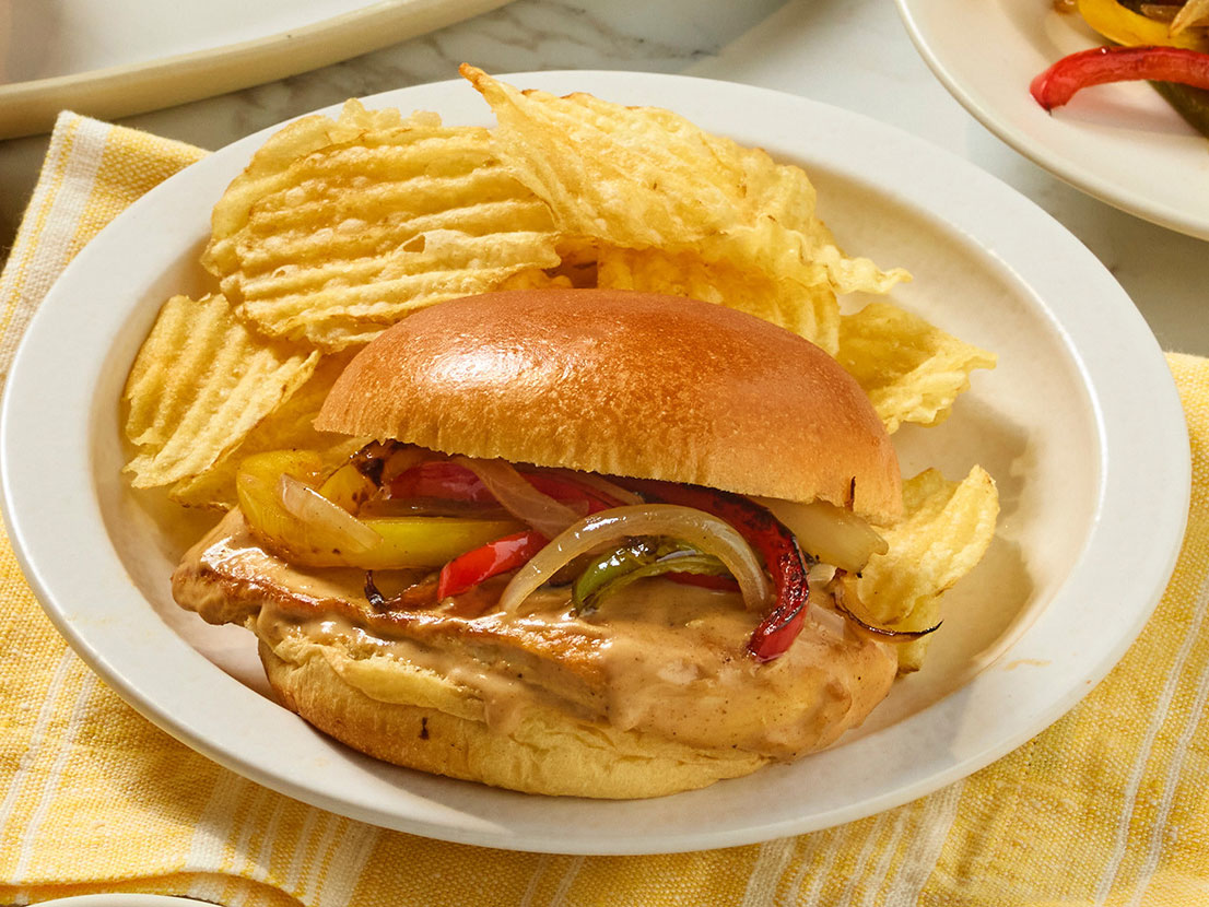 An image of prepared Smothered Cajun Chicken Sandwiches made with chicken, onion, bell pepper, Prego® Cajun Alfredo Pasta Sauce and Pepperidge Farm® Farmhouse® Brioche Hamburger Buns.