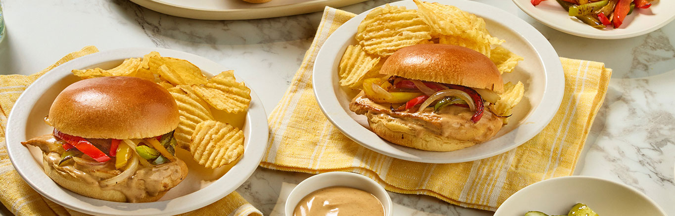 An image of prepared Smothered Cajun Chicken Sandwiches made with chicken, onion, bell pepper, Prego® Cajun Alfredo Pasta Sauce and Pepperidge Farm® Farmhouse® Brioche Hamburger Buns.