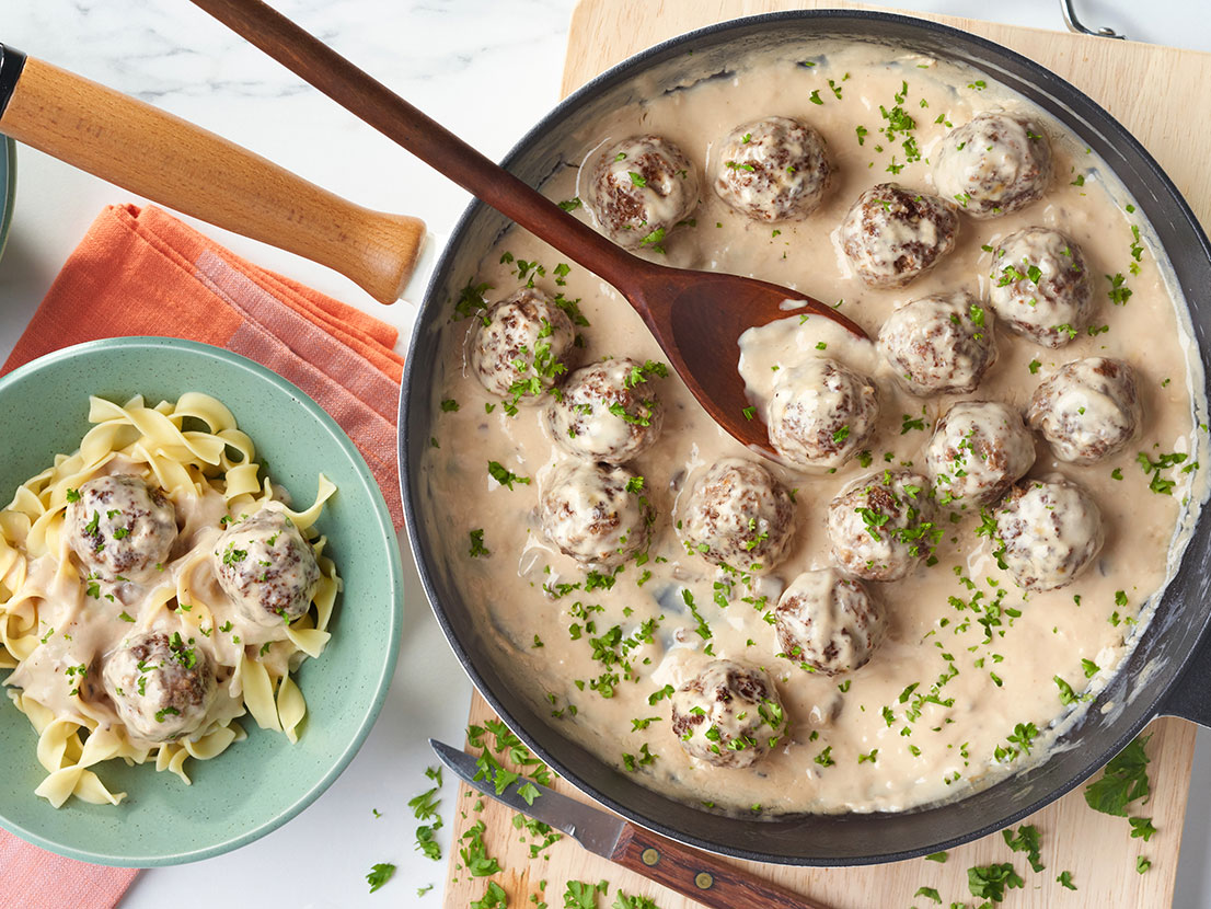 An image of prepared Swedish Meatballs made with ground turkey or ground beef, onion, Swanson® 50% Less Sodium Beef Broth, Campbell's® Condensed Cream of Mushroom Soup, sour cream and egg noodles.