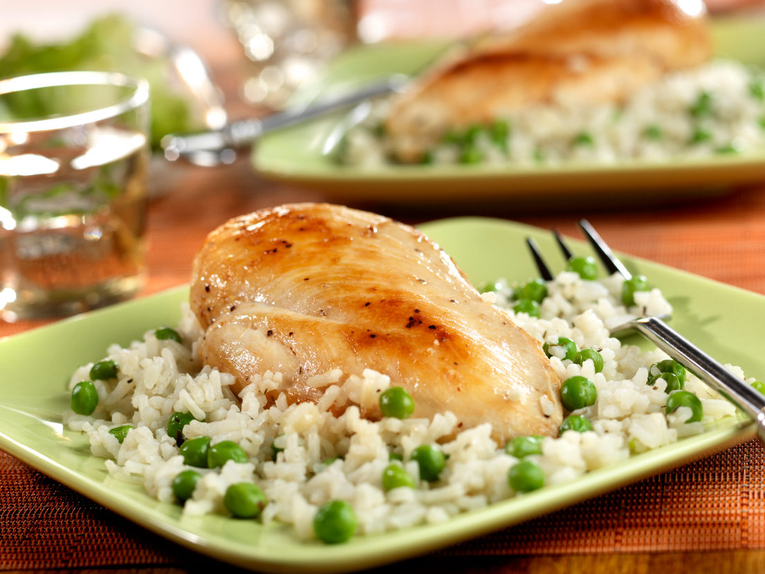 An image of prepared Chicken with Savory Herbed Rice made with chicken, Swanson® Chicken Broth instant white rice, peas and Parmesan cheese.