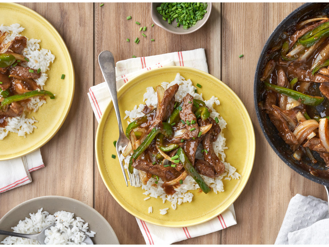 An image of prepared Easy Pepper Steak made with Swanson® Beef Broth, soy sauce, beef sirloin steak, bell peppers, onion and long grain white rice.