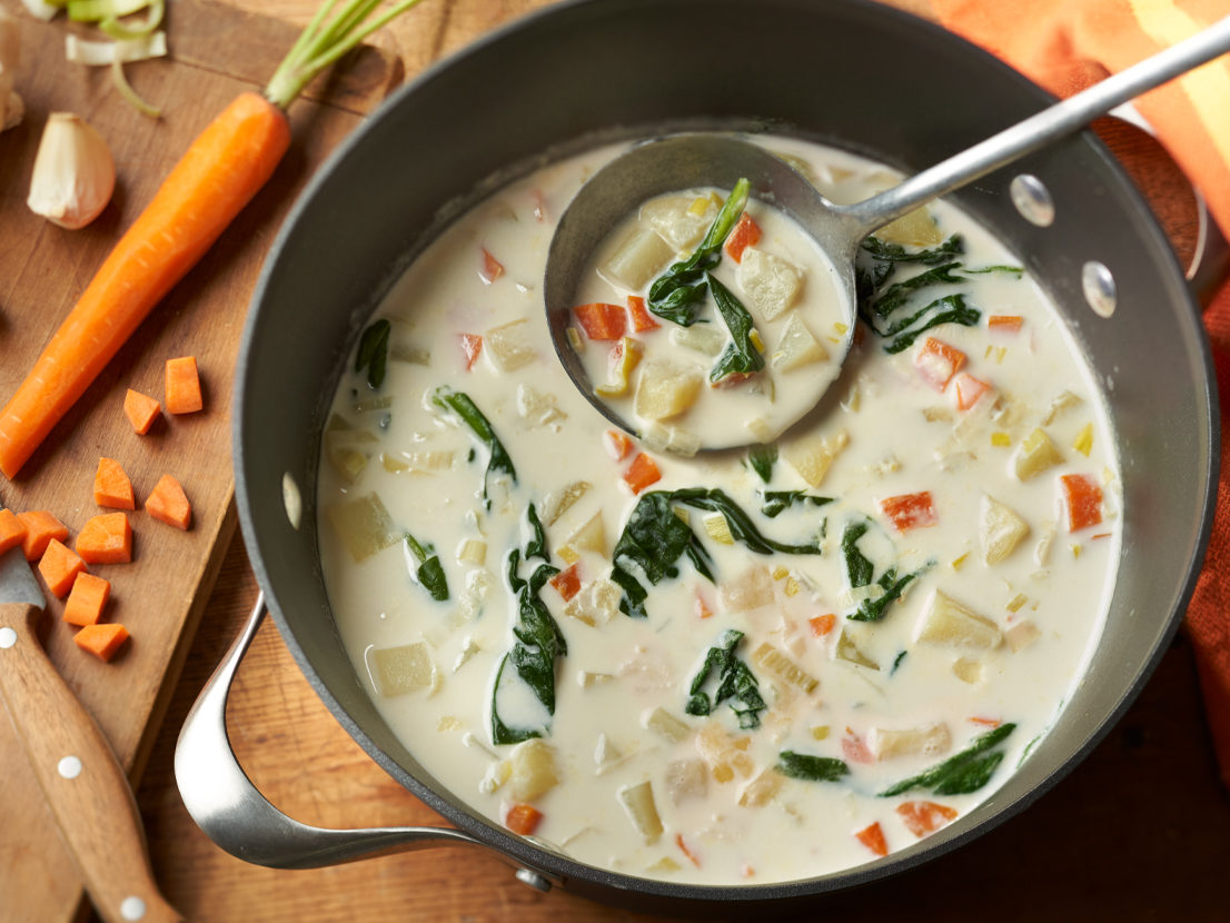 An image of prepared Garlicky Potato Leek Soup made with Yukon Gold potatoes, leeks, carrots, garlic, Swanson® Chicken Broth, light cream and baby spinach.
