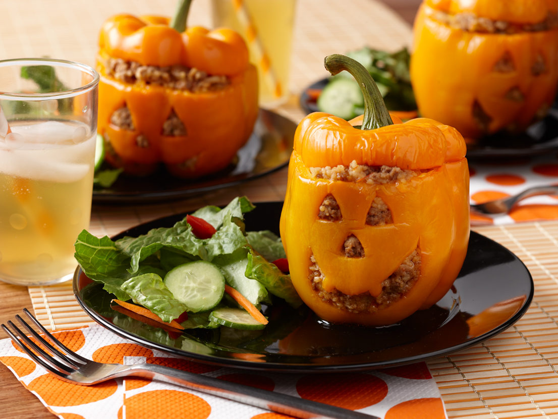 Image of prepared Halloween Jack O'Lantern Stuffed Peppers made with orange bell peppers, onion, ground turkey, Swanson® Chicken Broth, Pace® Picante Sauce, couscous and Cheddar cheese.