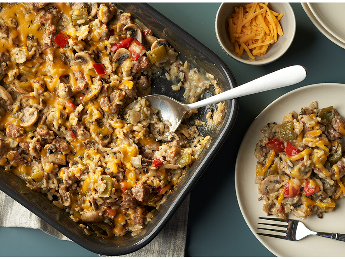 An image of prepared Hearty Sausage & Rice Casserole made with pork sausage, mushrooms, celery, bell pepper, onion, long grain and wild rice mix, Swanson® Chicken Broth, Campbell's Condensed Cream of Mushroom Soup and Cheddar cheese.