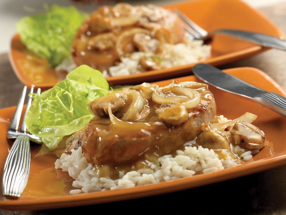 An image of the prepared Mustard Pork Chops made with Swanson® Beef Broth or Beef Stock, pork chops, mushrooms, onion and rice.