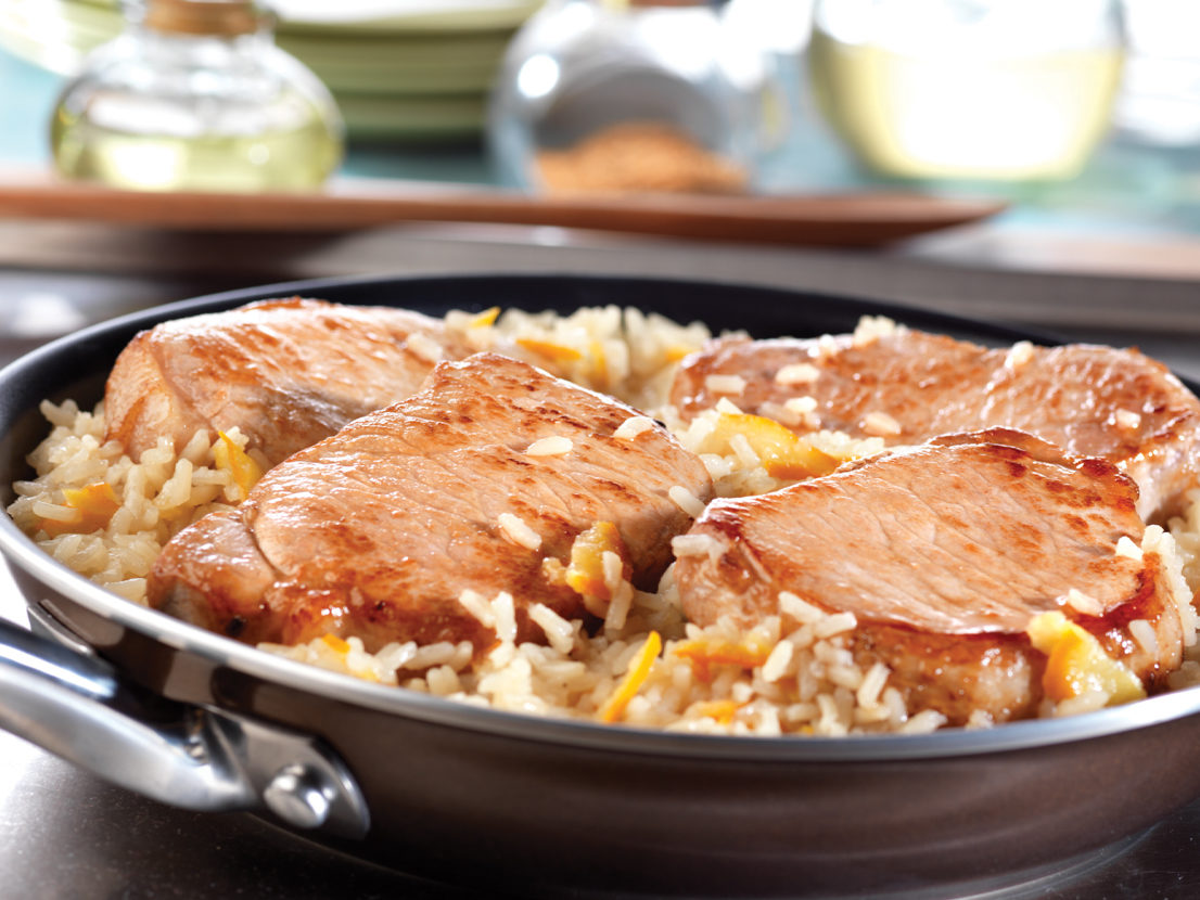 An image of prepared Quick Glazed Pork & Rice Skillet made with pork chops, onion, rice, Swanson® Chicken Broth, apricot preserves and Dijon-style mustard.
