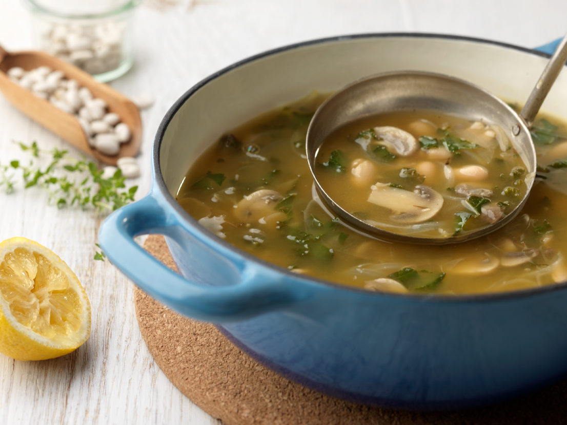 An image of prepared White Bean, Lemon & Kale Soup made with onion, garlic, kale, mushrooms, Swanson® Vegetable Broth, cannellini beans and lemon juice.