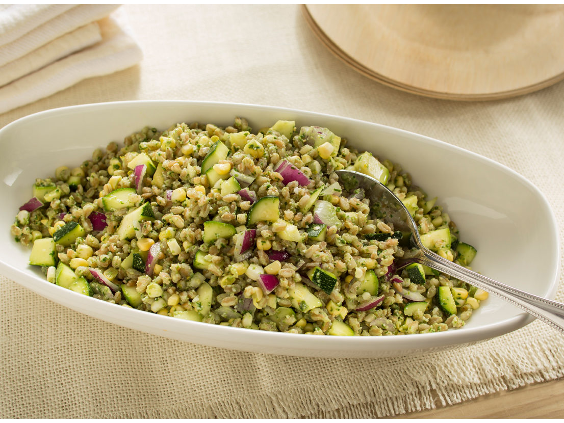 An image of prepared Zucchini Farro Salad with Homemade Pesto made with Swanson® Chicken Broth, basil, parsley, pine nuts, Parmesan cheese, farro, zucchini, corn and red onion.