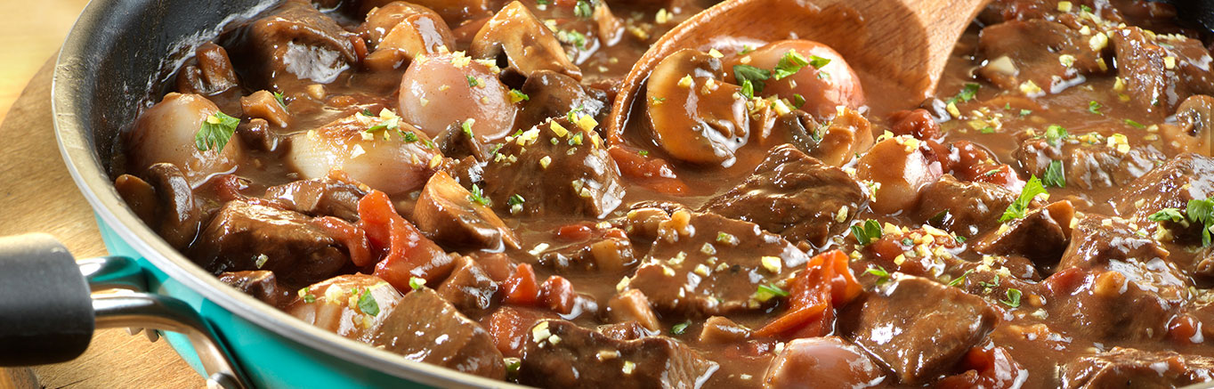 An image of prepared Braised Beef with Shallots and Mushrooms made with beef chuck roast, mushrooms, tomatoes and Swanson® Beef Stock.