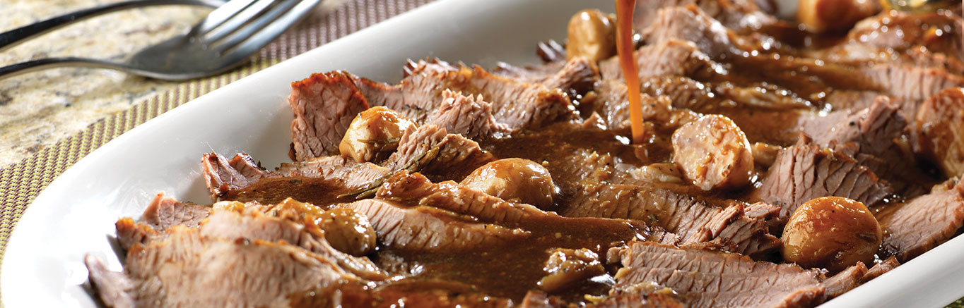 An image of prepared Braised Brisket with Garlic made with beef brisket, garlic, Swanson® Beef Stock and fresh herbs.