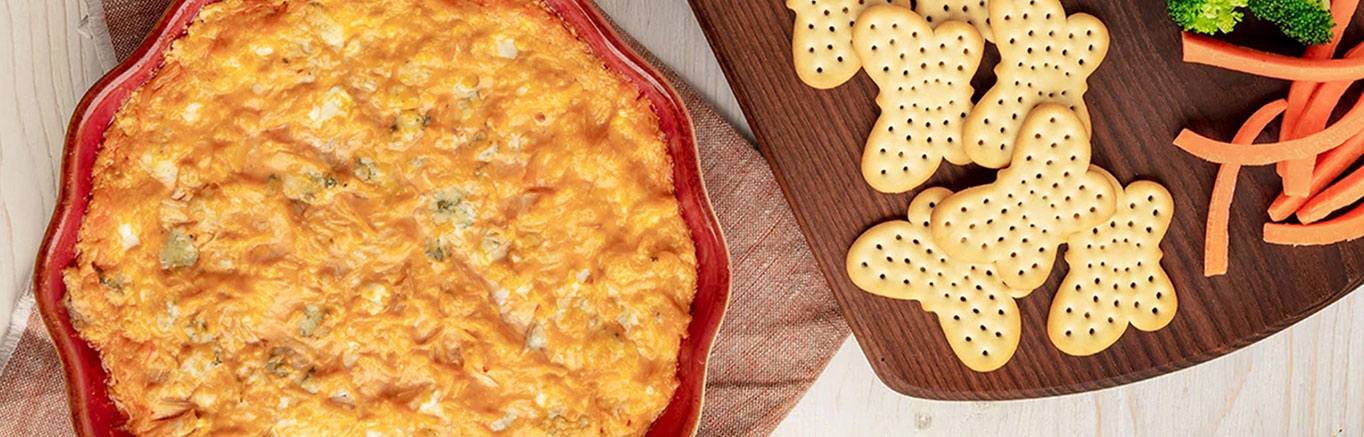 An image of prepared Buffalo Chicken Dip made with cream cheese, blue cheese, Franks® Redhot® Sauce, Swanson® Premium White Chunk Chicken Breast and Pepperidge Farm® Cracker Trio.