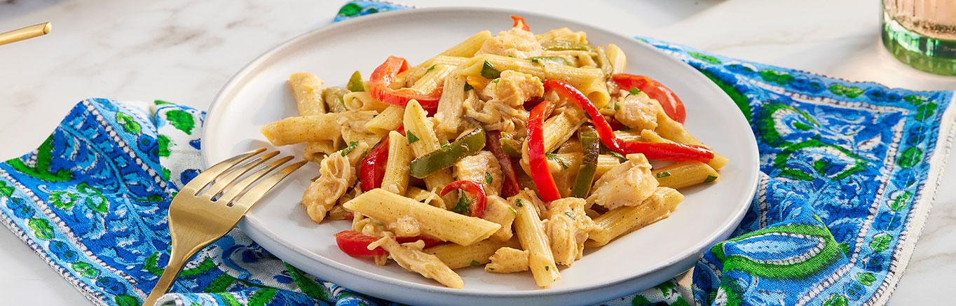 An image of prepared Cajun Chicken Alfredo made with bell pepper, garlic, Swanson® Natural Goodness® Chicken Broth, penne pasta, Swanson® Premium White Chicken, cream and Parmesan cheese.