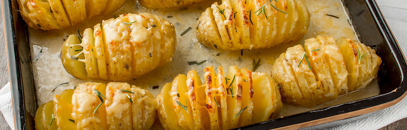 An image of prepared Cheesy Hasselback Potato Gratin made with Yukon Gold potatoes, onion, rosemary, Swanson® Chicken Broth, cream, Gouda cheese and Parmesan cheese.