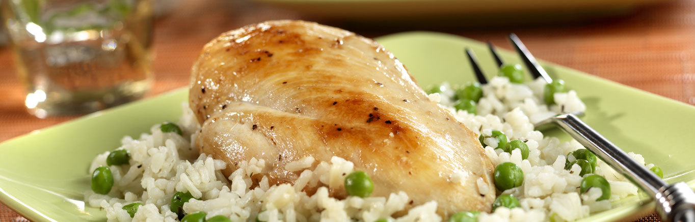 An image of prepared Chicken with Savory Herbed Rice made with chicken, Swanson® Chicken Broth instant white rice, peas and Parmesan cheese.