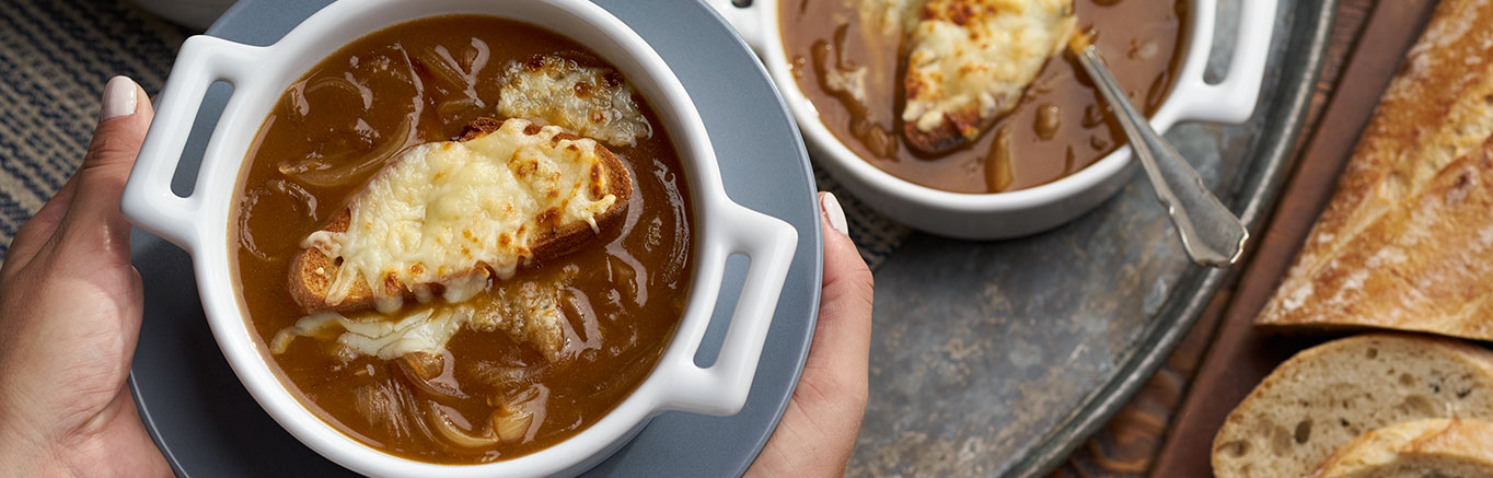 An image of prepared French Onion Soup made with onions, Swanson® Beef Broth, Swanson® Chicken Broth, dry vermouth, Gruyère cheese, mozzarella cheese and French bread.