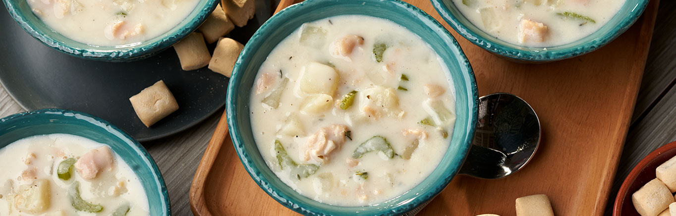 An image of prepared Creamy New England Clam Chowder made with Swanson® Chicken Broth, potatoes, celery, onion and clams.