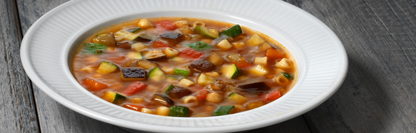 An image of prepared Easy Minestrone Soup made with onion, red bell pepper, eggplant, zucchini, Swanson® Vegetable Broth, ditalini pasta, and chickpeas.