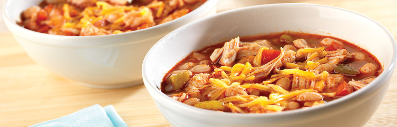 An image of prepared Easy Chicken Chili with White Beans made with onion, Swanson® Premium White Chunk Chicken, white navy beans, pepper, Swanson® Chicken Broth, green chiles and Cheddar cheese.