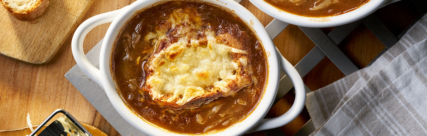 An image of prepared French Onion Soup made with onions, Swanson® Beef Broth, white wine, Swiss cheese, and French bread.