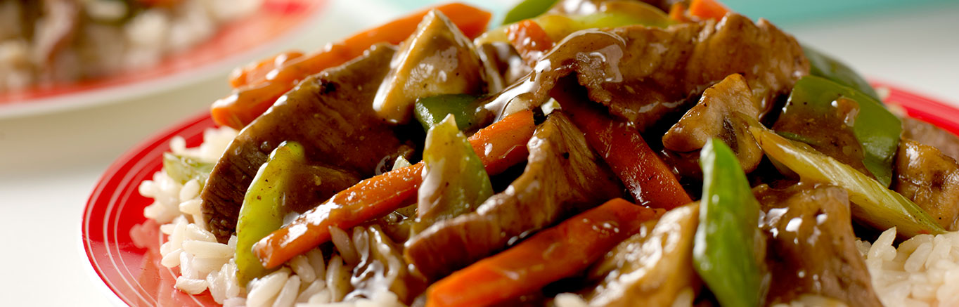 An image of prepared Ginger-Beef Stir-Fry made with Swanson® Beef Broth, soy sauce, boneless beef sirloin steak, green pepper, carrot, mushrooms, celery, onion, ginger and long grain white rice.