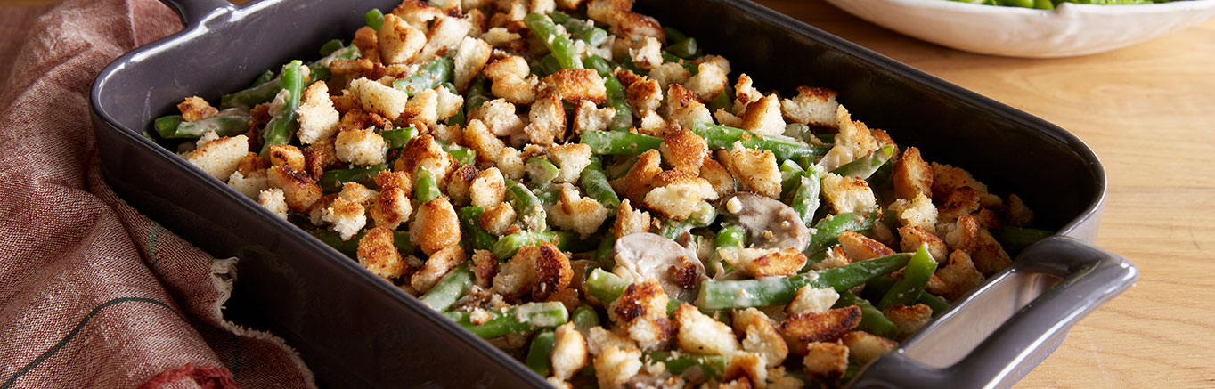 An image of prepared Green Bean Mushroom Madeira Casserole made with mushrooms, shallots, Madeira wine, Swanson® Chicken Broth, green beans, mascarpone and Italian bread.