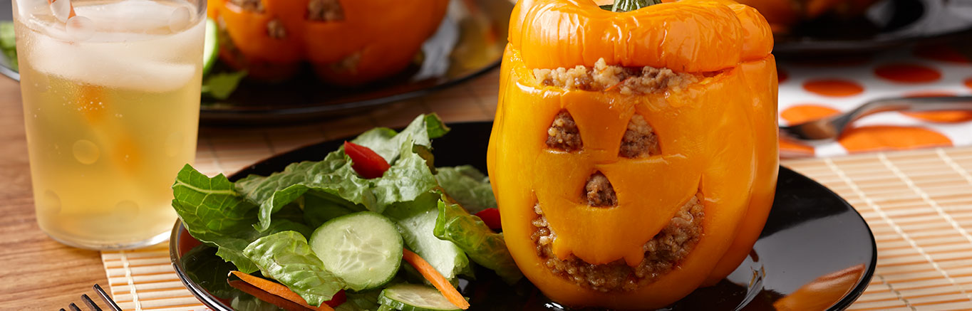 Image of prepared Halloween Jack O'Lantern Stuffed Peppers made with orange bell peppers, onion, ground turkey, Swanson® Chicken Broth, Pace® Picante Sauce, couscous and Cheddar cheese.