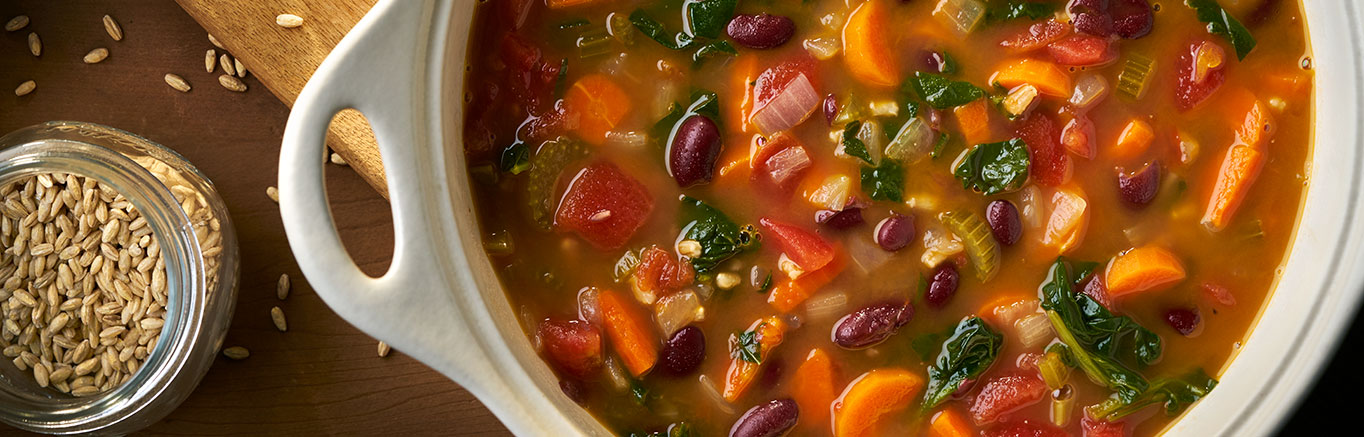An image of prepared Hearty Bean & Barley Soup made with carrots, celery, onion, Swanson® Vegetable Broth, kidney beans, tomatoes, barley and spinach.
