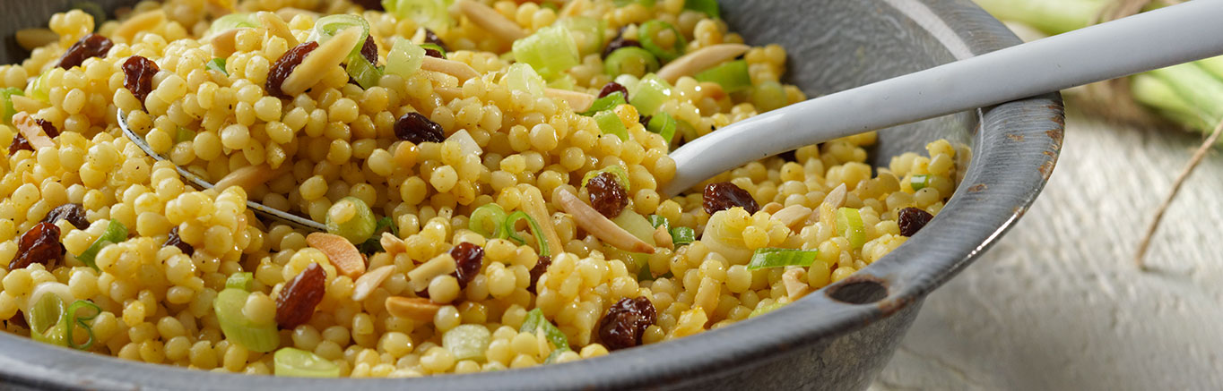An image of prepared Israeli Couscous Salad made with couscous, curry, Swanson® Vegetable Broth, raisins and almonds.