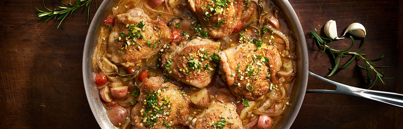 Image of prepared Lemon Rosemary Chicken made with chicken thighs, onions, fennel, grape tomatoes, baby red potatoes, Swanson® Chicken Bone Broth, rosemary and lemon.