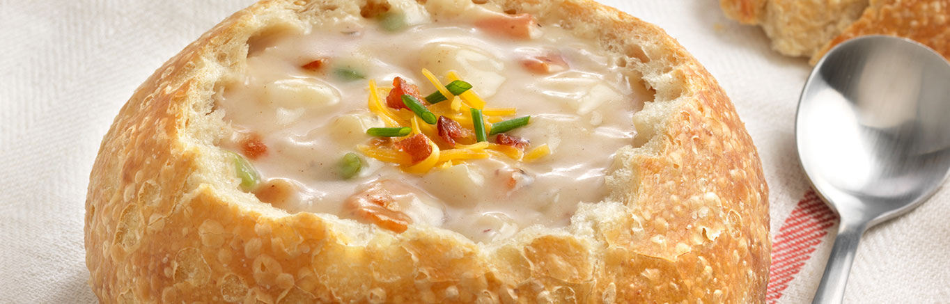 An image of prepared Loaded Potato Soup made with bacon, russet potatoes, onion, garlic, Swanson® Chicken Broth and green onion or chives.