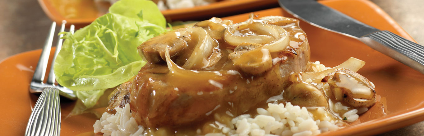 An image of the prepared Mustard Pork Chops made with Swanson® Beef Broth or Beef Stock, pork chops, mushrooms, onion and rice.