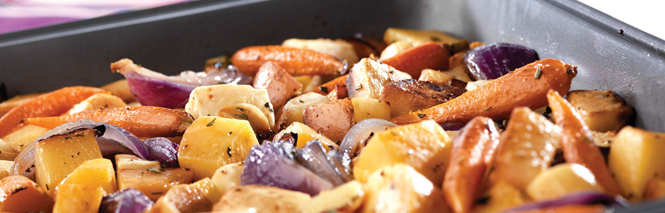 An image of prepared Oven-Roasted Root Vegetables made with red potatoes, baby carrots, celery root, rutabaga, red onion, parsnip, garlic, rosemary and Swanson® Vegetable Broth.