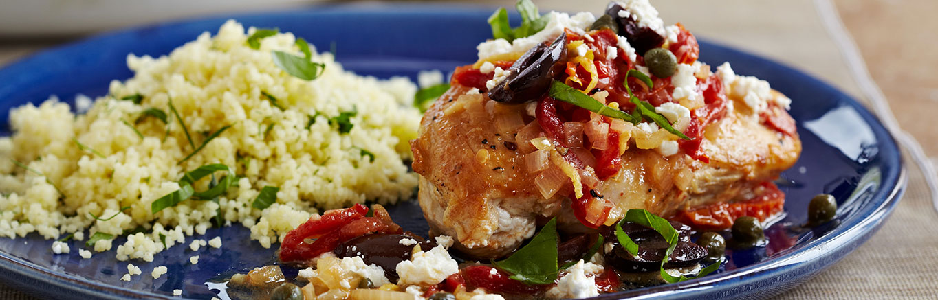 An image of prepared Pan-Seared Mediterranean Chicken made with Swanson® Chicken Stock, sun-dried tomatoes, chicken, kalamata olives, capers, feta and couscous or orzo.