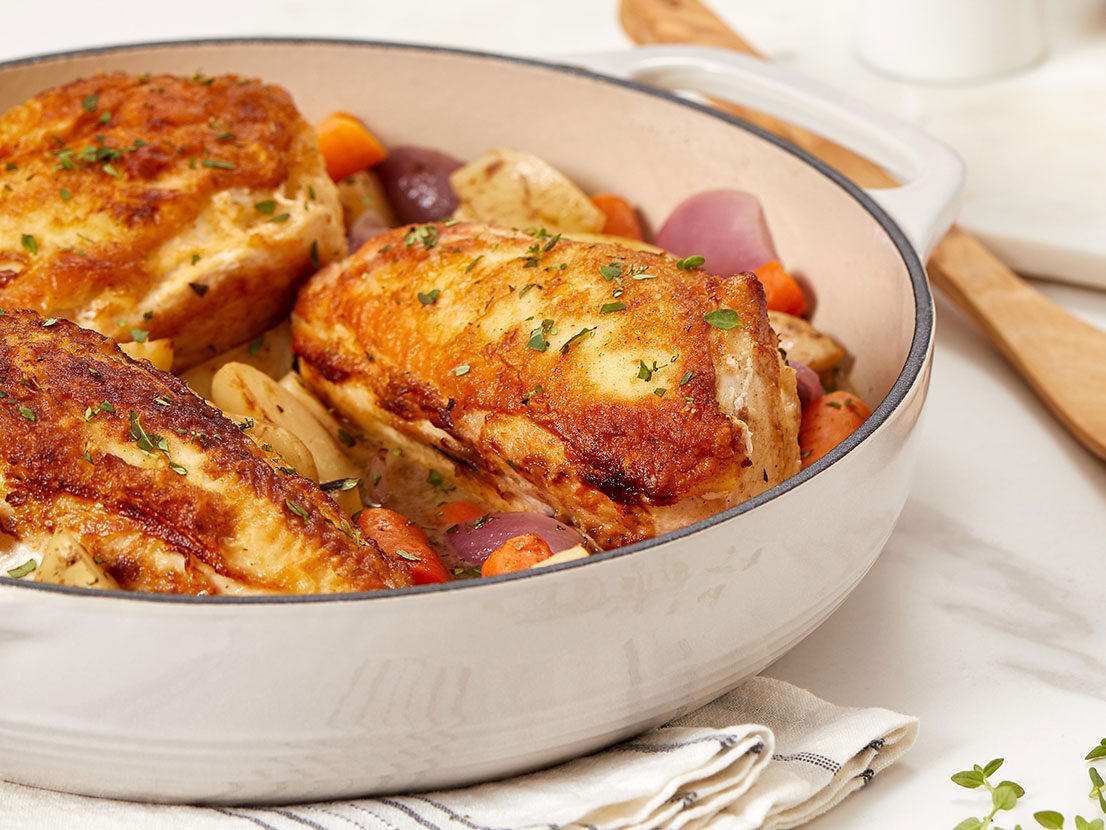 An image of prepared Pan-Roasted Chicken with Vegetables & Herbs made with chicken, red onion, potatoes, carrots, Swanson® Chicken Stock, lemon and fresh herbs.