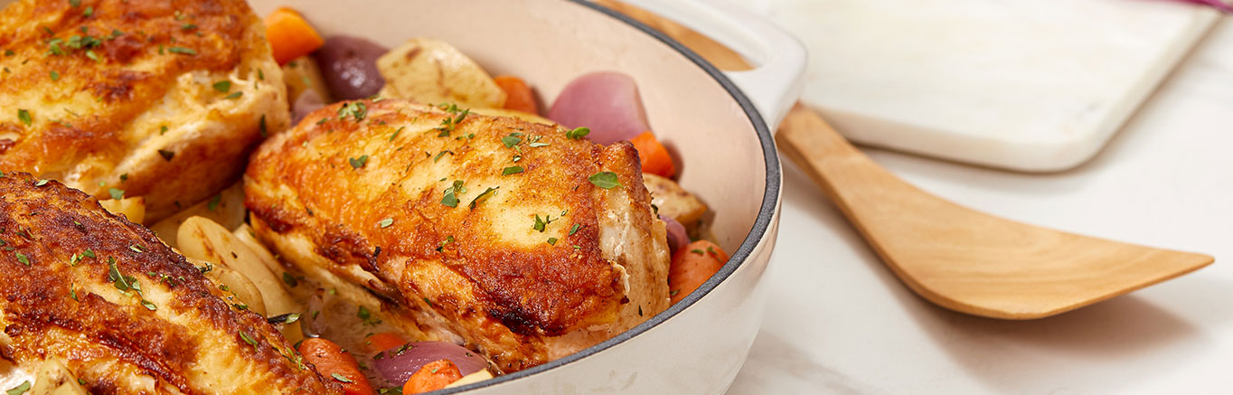 An image of prepared Pan-Roasted Chicken with Vegetables & Herbs made with chicken, red onion, potatoes, carrots, Swanson® Chicken Stock, lemon and fresh herbs.