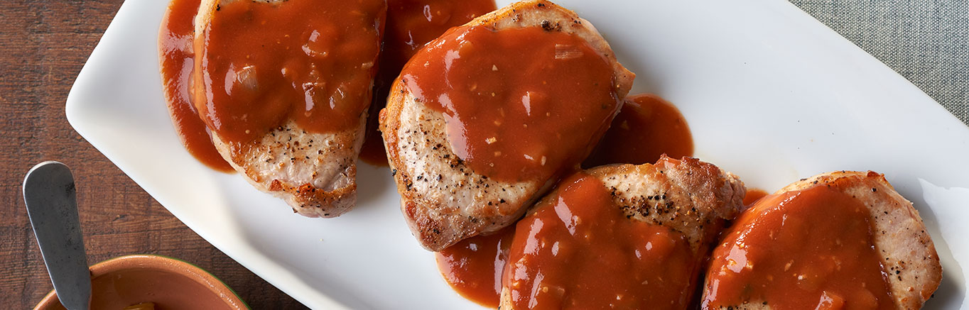 An image of prepared Pork Diane made with pork chops, brandy, Campbell's® Condensed Tomato Soup and Swanson® Chicken Broth.