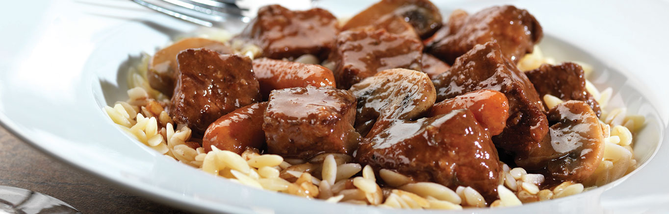 An image of prepared Pressure Cooker Beef Bourguignon made with steak, mushrooms, carrots, Swanson® Beef Broth or Beef Stock and Burgundy wine.